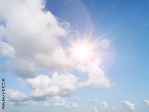 Blue sky with white fluffy clouds and sun reflection. Sunny background. Sun appear directly above Thailand. The afternoon summer sun shines on a beautiful sky with clouds.