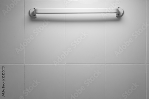 Clothes rack on the white tile wall in the bathroom