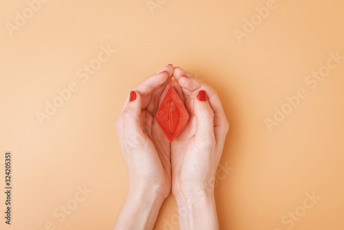 small red paper boat in female palms. conceptual abstract image of the vagina photo