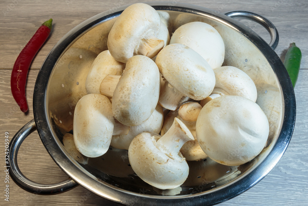Raw champignon heap ready for cooking. Fresh agaricus in a colander. Raw champignon heap ready for cooking. Fresh agaricus in a colander.