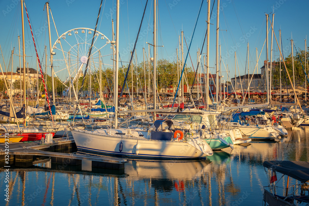 Obraz premium Colorful sailboats at sunset in the old harbor of La Rochelle, France