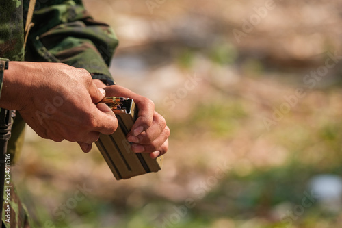 Closeup of gunner reload his pistol magazine, gun weapon, bullet from bullet block with blur black