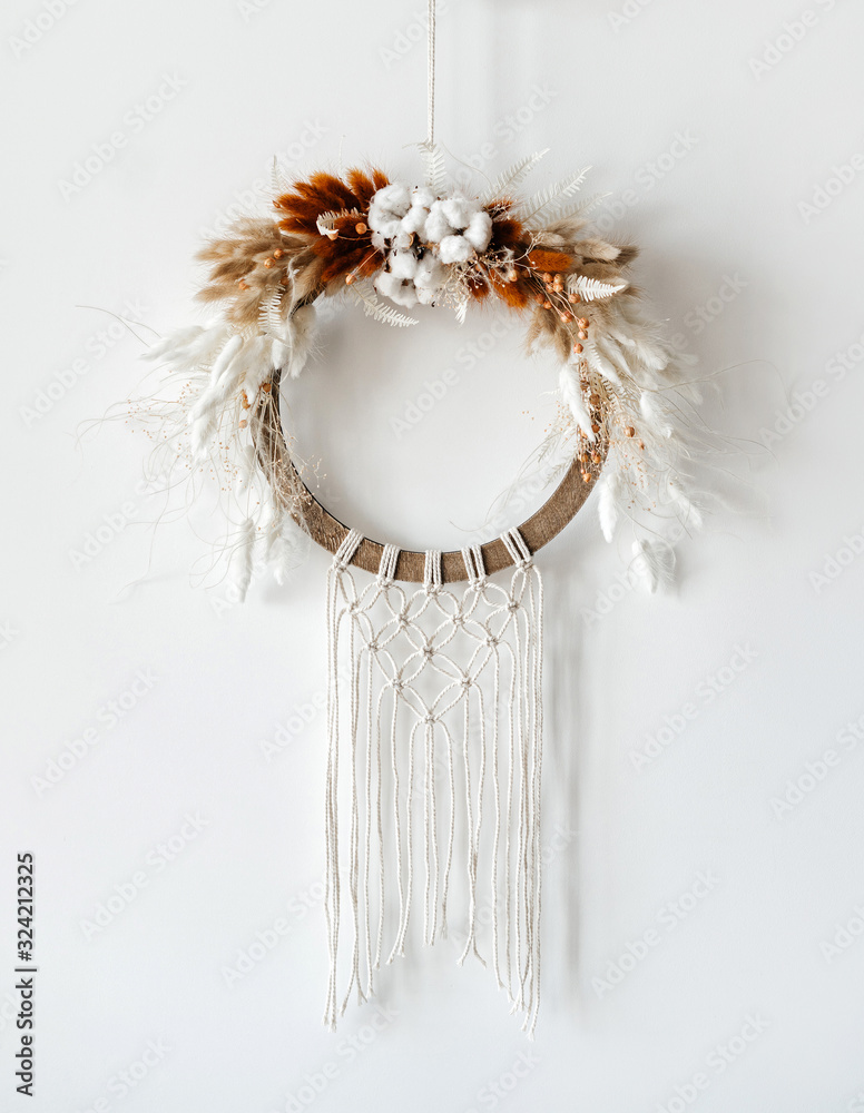 wreath and dried flowers of Dried Bunny Tail, cotton and macrame, on a light background. Creative greeting card for a creative person.