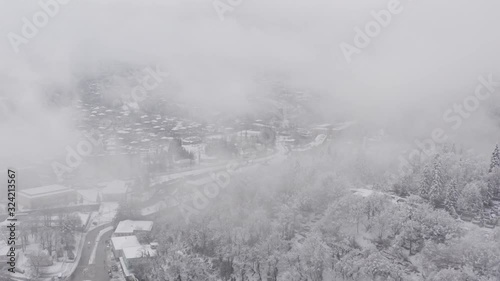 Flying in the clouds above snowy town Tkibuli, shoot in country of Georgia,  with drone 4K