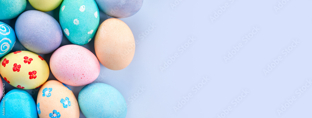 Obraz premium Colorful Easter eggs dyed by colored water with beautiful pattern on a pale blue background, design concept of holiday activity, top view, full frame.