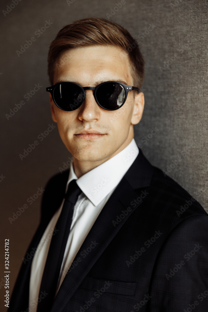 Handsome groom on a black suit with black glasses Handsome groom on a black suit with black glasses