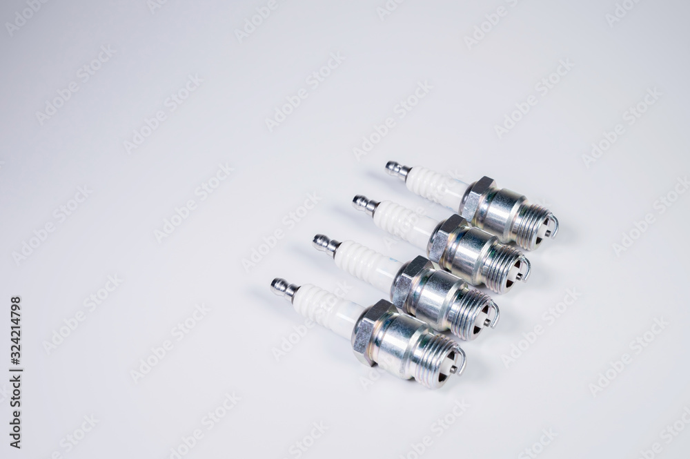 Subject shooting on a gray background. new four spark plugs, spare parts for a gasoline engine. The concept of new auto parts and maintenance Subject shooting on a gray background. new four spark plugs, spare parts for a gasoline engine. The concept of new auto parts and maintenance