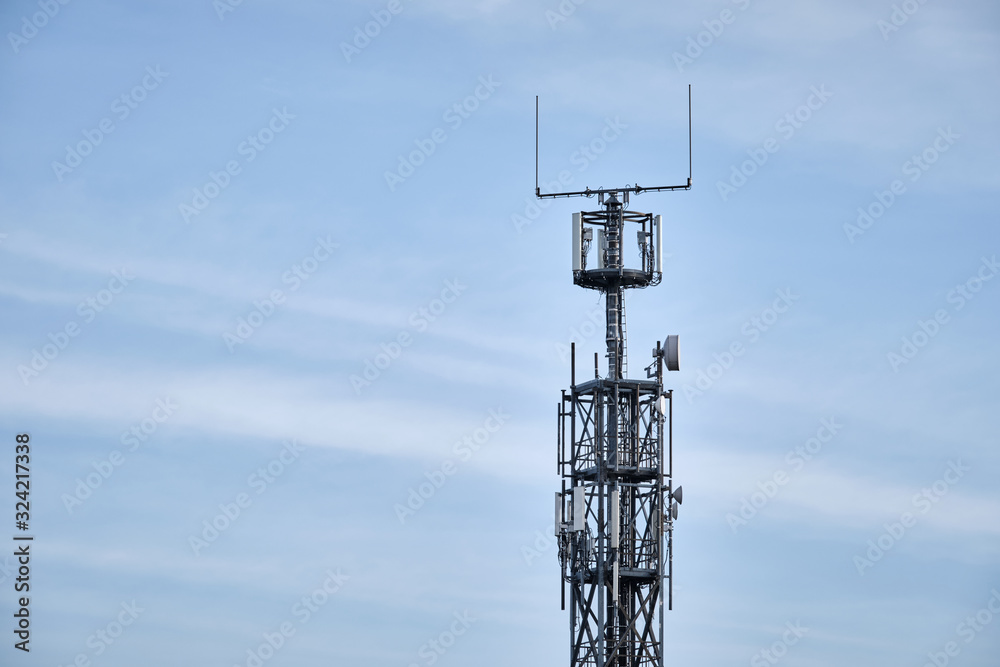 Close-up of lattice mast with base station for mobile communications against blue sky with clouds. Seen in Germany in February Close-up of lattice mast with base station for mobile communications against blue sky with clouds. Seen in Germany in February