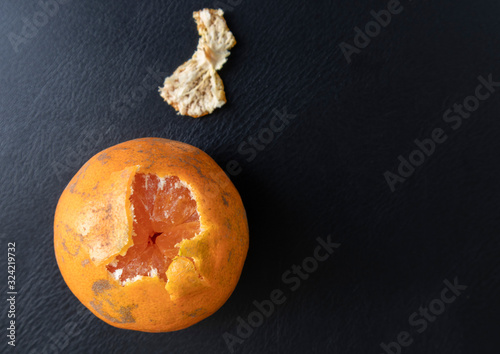 Top view, orange peeled by hand, placing on floor. Healthy fresh orange.Design isolated on black. Healthy diet concept. Peeled oranges placed on black floor. Concept differenc in same place photo