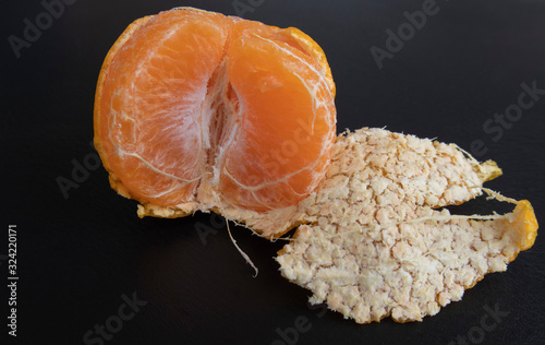 orange peeled by hand, placing orange on the floor. Healthy fresh orange.Design isolated on black. Healthy diet concept. Peeled oranges placed on black floor. Concept difference in same place