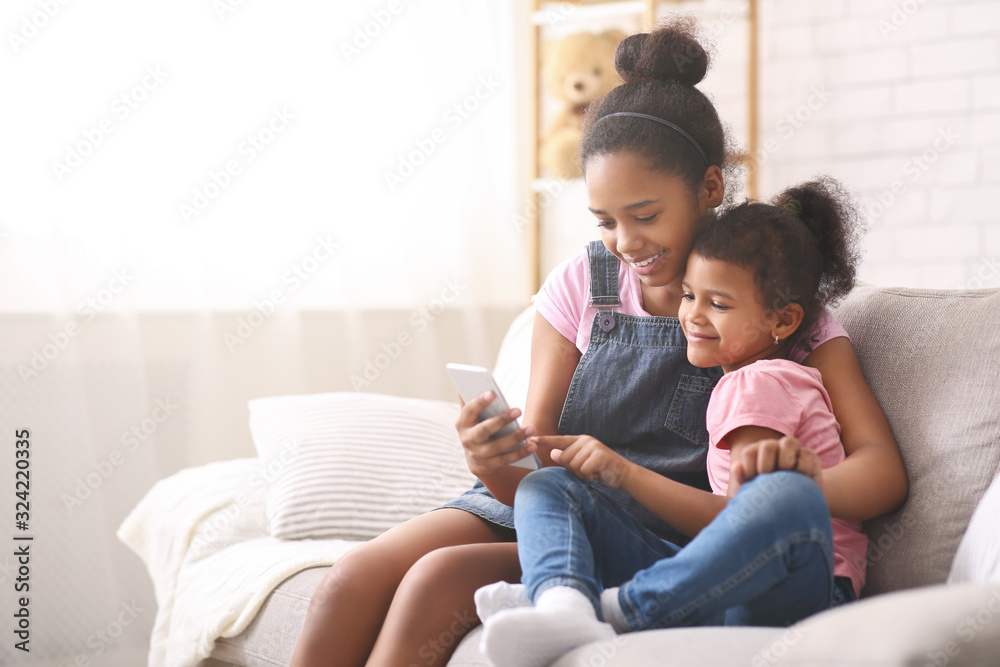 African american sisters watching cartoons on mobile phone African american sisters watching cartoons on mobile phone