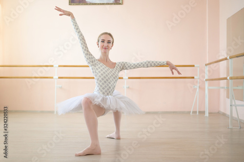 Fotografie A very flexible ballerina in a tutu stands in a plie in a class with ballet machines
