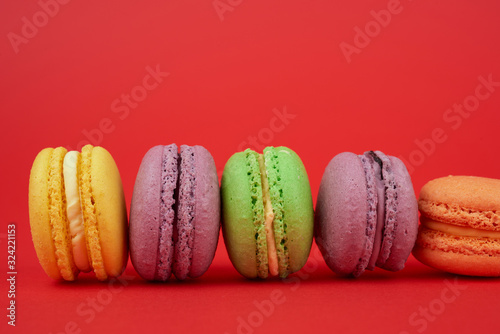 yellow, purple, green round baked macarons cakes on a red background