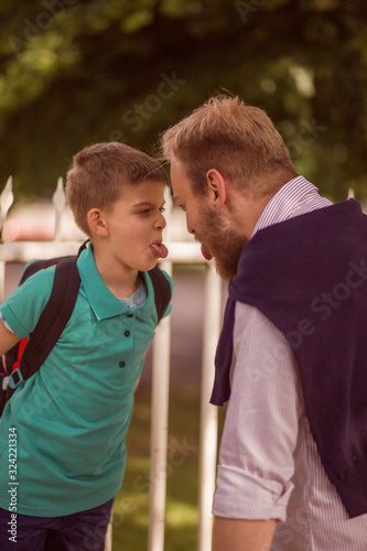 young father and his little son, making a face to each other. Tongue out, face to face.