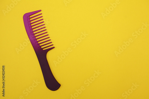 purple hairbrush for hair on a yellow background, space for text.