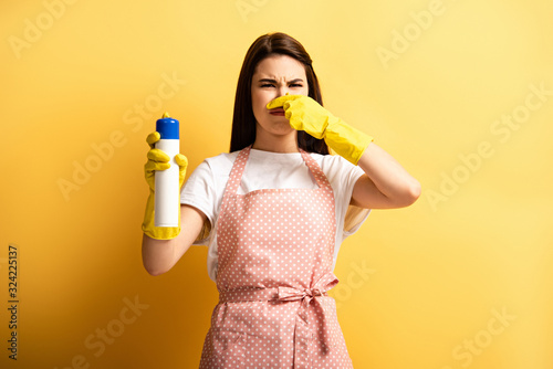 Bilde på lerret displeased housewife in apron and rubber gloves plugging hose with hand while ho