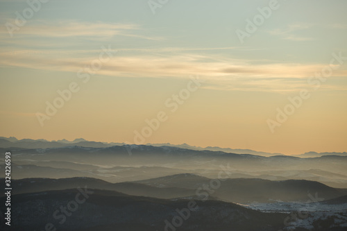 Fototapeta Naklejka Na Ścianę i Meble -  Beautiful view of the mountain range partially covered with snow just before sunset. Partly orange sunset sky