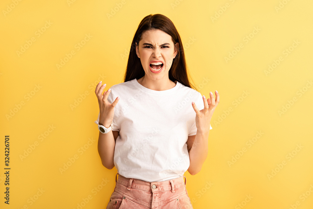 irritated girl gesturing and shouting while showing indignation gesture isolated on yellow irritated girl gesturing and shouting while showing indignation gesture isolated on yellow
