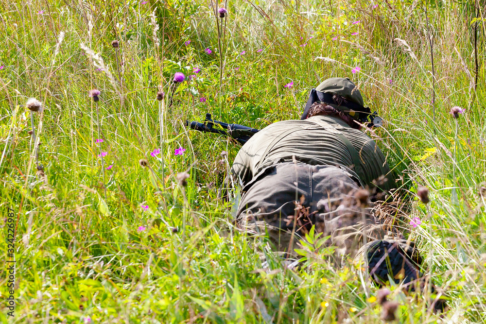 Two people playing airsoft hid in ambush behind fence Two people playing airsoft hid in ambush behind fence