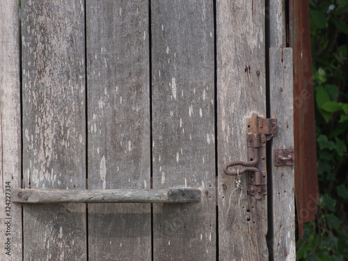 old aged weathered wood surface of an old country house door with wooden grip and rusty bolt.