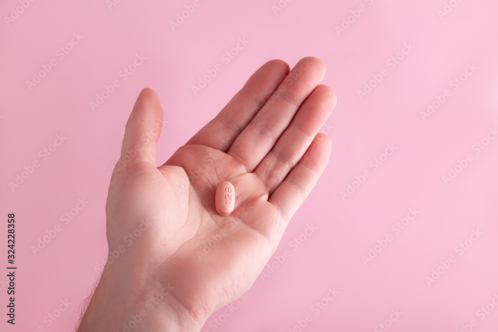 Men holding hiv therapy pills on pink background. Men holding hiv therapy pills on pink background.
