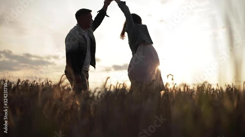 Stock footage of beautiful young couple dancing in the field at sunset. Pregnant wife and loving husband spending their time together dancing in the meadow in the evening.