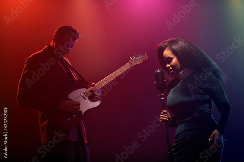 A jazz singer and guitarist perform on stage.