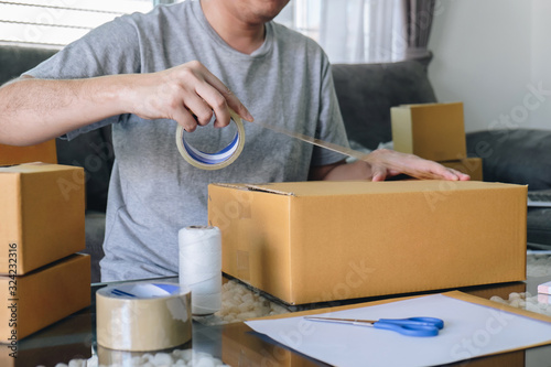 Small business parcel for shipment to client, Young entrepreneur SME freelance man working with packaging their packages box delivery online market on purchase order and preparing package product