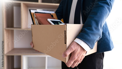 Businessmen are holding resignation document and packing personal company on brown cardboard box changing work, resign concept