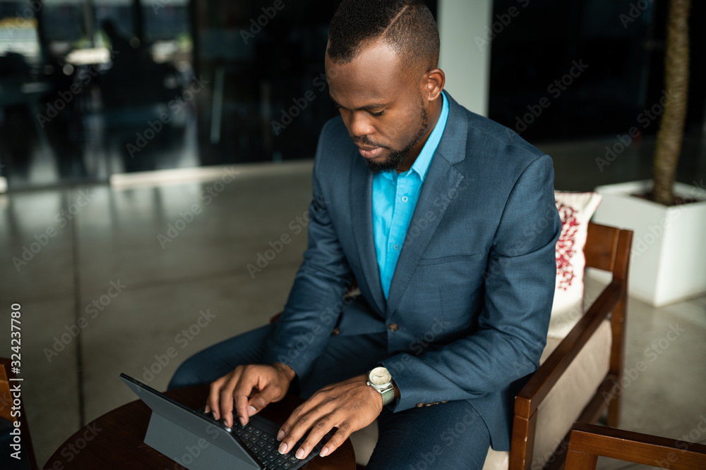 © JonoErasmus - African businessman using a digital tablet in an office lobby © JonoErasmus - African businessman using a digital tablet in an office lobby