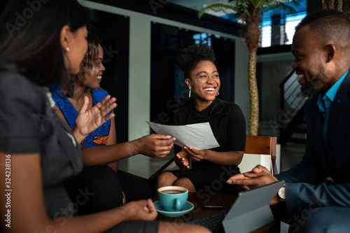 Laughing group of African businesspeople discussing paperwork in an office photo