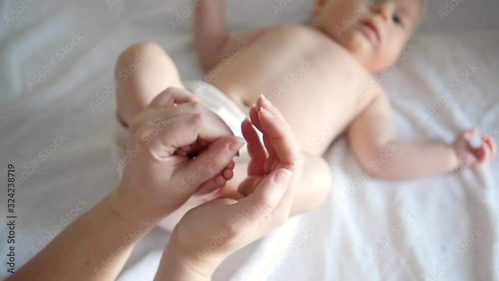 Close up little baby legs in mother and father hands. Hands of father gently hug mother's hands holding baby legs. Loving family, well-being of the child Close up little baby legs in mother and father hands. Hands of father gently hug mother's hands holding baby legs. Loving family, well-being of the child