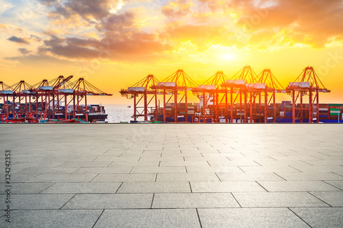 Empty square floor and industrial container terminal at beautiful sunset in Shanghai.