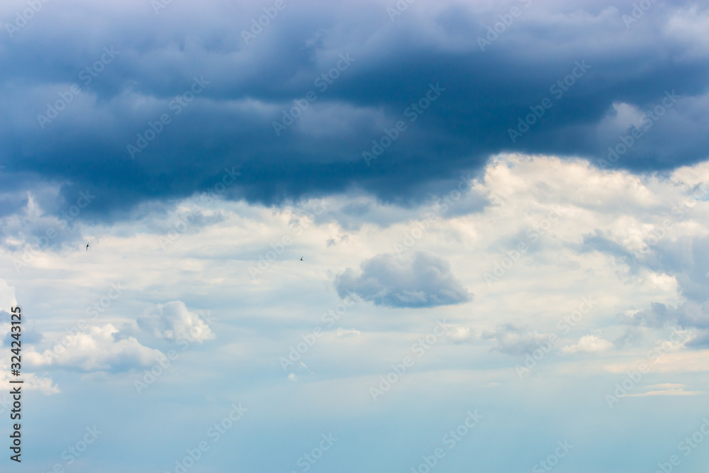 Stormy sky cloudscape with white cumulus rain clouds. Weather a sky peeps through thunderclouds, nature cloudy weather