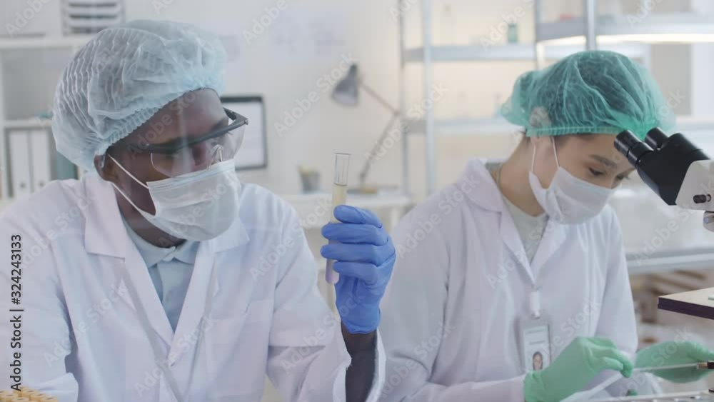 Lockdown of two diverse researchers conducting chemical experiment in laboratory Lockdown of two diverse researchers conducting chemical experiment in laboratory
