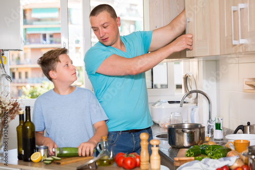 Father and his young son are satisfied of cooking soup together