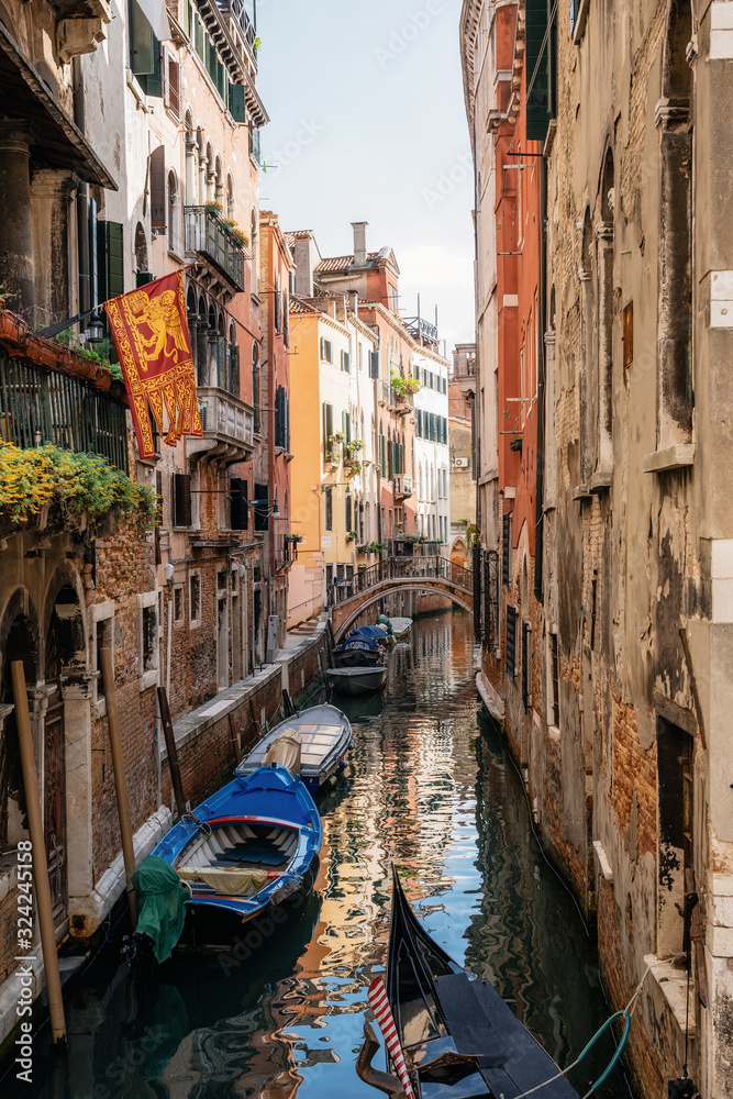 Boats in narrow canal between ancient houses, Venice, Italy