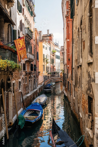 Boats in narrow canal between ancient houses, Venice, Italy