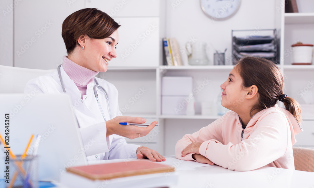 Fototapeta premium Doctor fills patient card for girl
