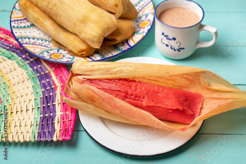 Mexican sweet tamales with strawberry jam on turquoise background photo