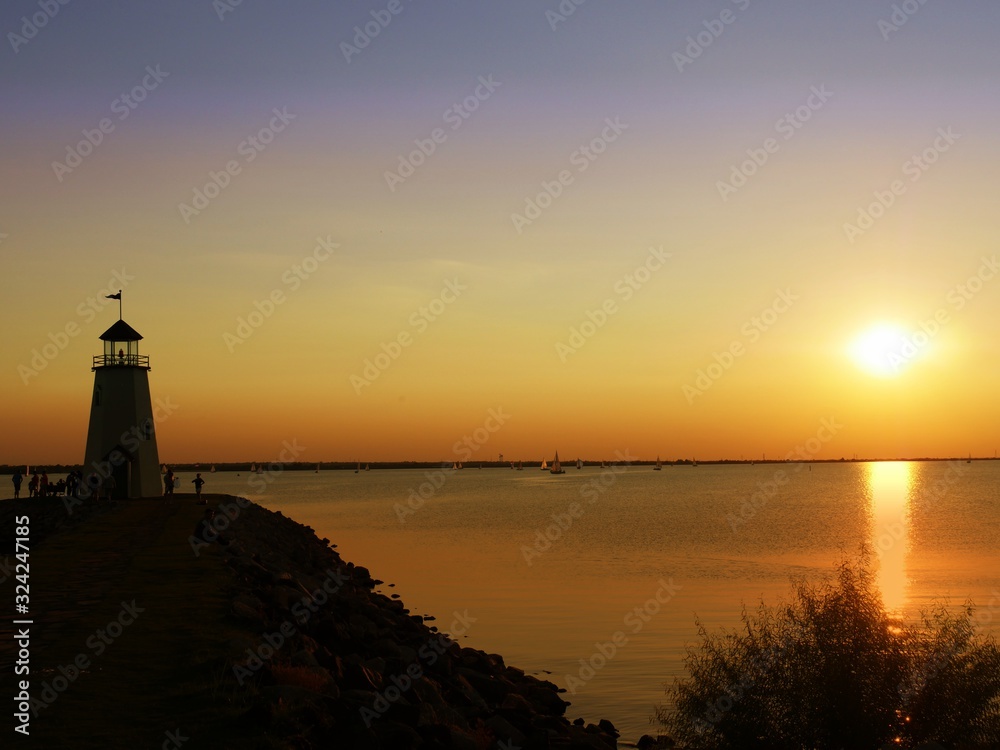 Silhouette of a lighthouse with an aazing sunset by the lake reflected in the waters