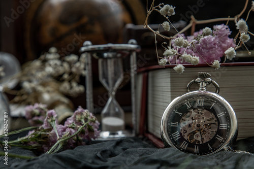 Pocket watch, blur stack of old book, hourglass, vintage binocular and world desk globe on dark background.