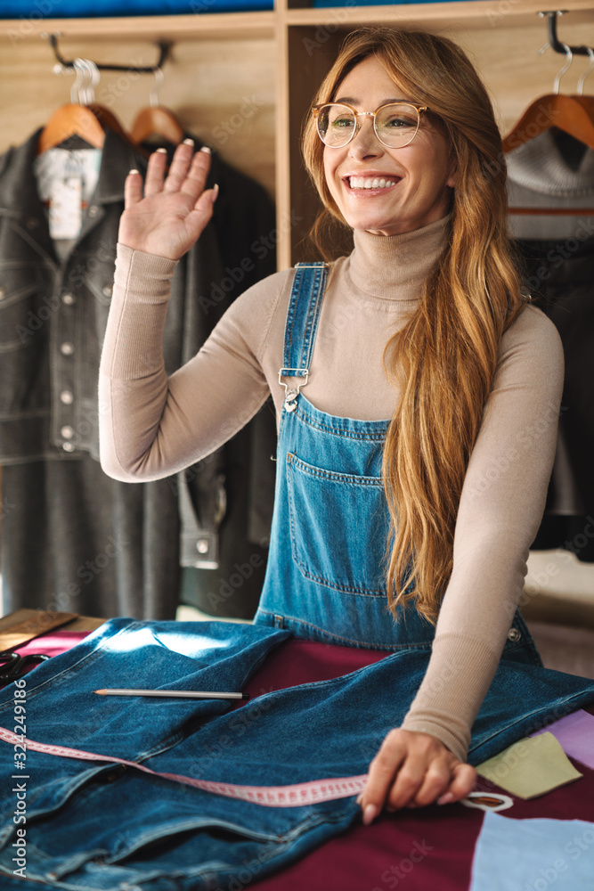 Φωτογραφία Photo of smiling woman seamstress waving hand and measuring jeans