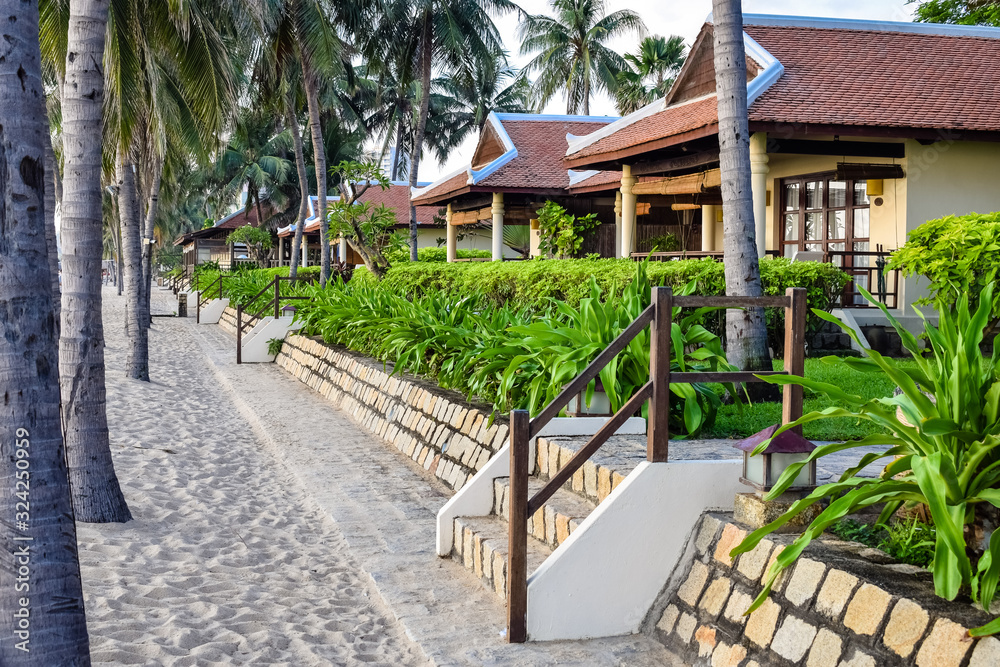 Hotels for tourists on beach in the tropics with palm trees and a staircase