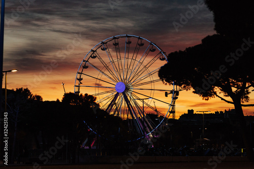 Colorful sky and Ferris wheel. Sunset through a Ferris Wheel in Antibes, France.Silhouette of giant ferris wheel on sunset. Illuminated Ferris wheel at sunset. 
