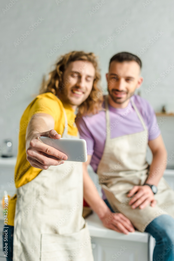 selective focus of homosexual men in aprons taking selfie selective focus of homosexual men in aprons taking selfie