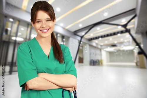 Attractive young female doctor with blurred hospital interior on background