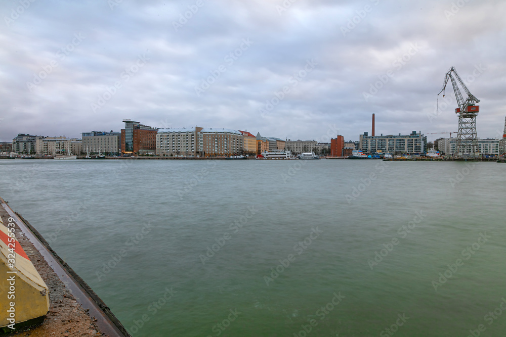 City working area, cargo port with cranes on the seashore. Helsinki panorama, Finland - February 18, 2020: Lautasaari island in cloudy weather. Early morning.