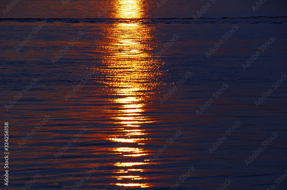 Vibrant rich sunset colors reflected in the ripples of the ocean Vibrant rich sunset colors reflected in the ripples of the ocean
