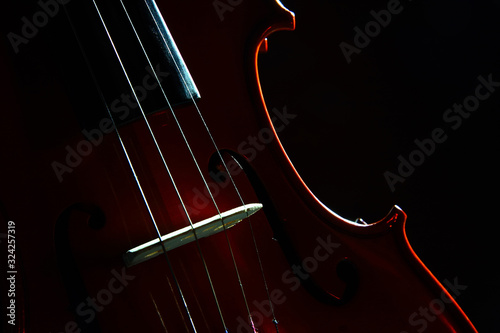 Detalle de violín con enfoque selectivo y fondo oscuro en clave baja. photo